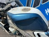 une moto bleue et blanche garée devant un bus bleu
