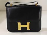 sac à main en cuir noir orné d'un logo « h » doré sur le devant