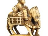 ivory figurine of a man riding a horse with a basket on his back