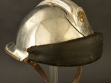 an old silver helmet on a metal stand against a black background