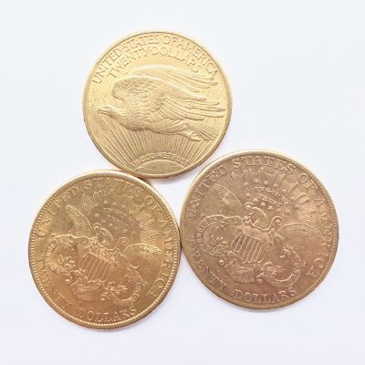 trois types différents de pièces d'or sur une surface blanche
