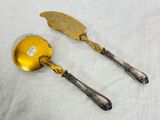 pair of gold plated serving utensils on a white tablecloth