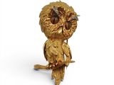 une image représentant une figurine en or en forme de chouette perchée sur une branche d'arbre