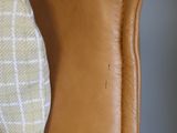 a brown leather chair with a plaid pillow on top of it