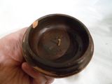 a person holding a small brown bowl in their hand
