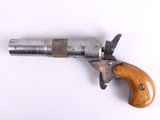 un vieux pistolet avec une poignée en bois sur une surface blanche