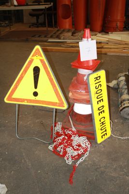 un panneau d'avertissement et un cône de signalisation posés au sol
