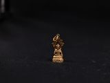 a small gold statue of a person sitting on top of a black surface