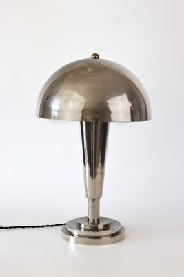 une photo d'une lampe de table argentée posée sur une surface blanche