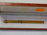 un stylo doré dans un coffret rouge posé sur une surface blanche