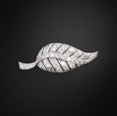 a close up of a diamond leaf broochle on a black background