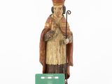 wooden figurine of a man with a staff and a green card