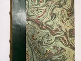 un vieux livre posé sur une table blanche à côté d'un livre noir