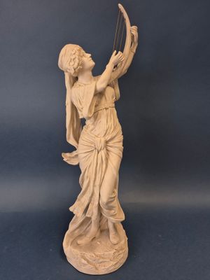 statue d'une femme tenant une harpe sur fond bleu
