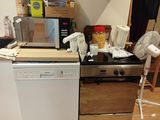 une cuisine équipée d'une cuisinière, d'un lave-vaisselle, d'un micro-ondes et d'autres ustensiles posés sur le plan de travail