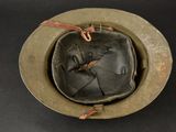 an old military helmet with a leather strap on a black surface