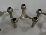 three silver metal candlesticks are sitting on a white surface