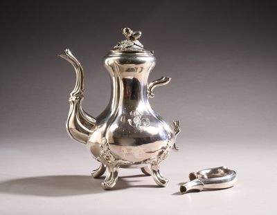 a silver tea pot sitting on a table next to a spoon