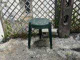 a small green stool sitting on a cement patio