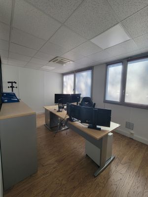 une pièce équipée d'un bureau, de deux écrans et d'un téléviseur