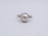 a close up of a white pearl ring on a white surface