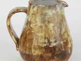 a brown pitcher sitting on a table with a white background