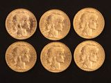 six souverains d'or de tailles et de formes différentes posés sur un fond noir