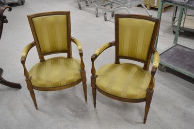 une paire de fauteuils rembourrés jaunes dans une pièce où l'on aperçoit de nombreux meubles à l'arrière-plan