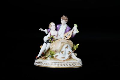 une figurine représentant un homme et une femme assis sur un banc