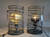 two metal lamps with a light bulb inside of them on a table