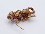 an image of a gold and black leopard broochle with a stick