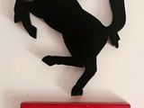 un cheval noir debout sur ses pattes arrière, perché sur une boîte rouge