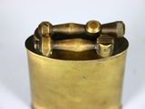 a small brass container with a handle on a white surface