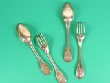 three silver spoons and two silver forks on a green surface