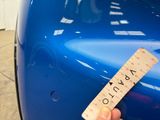 a person holding a ruler in front of a blue car