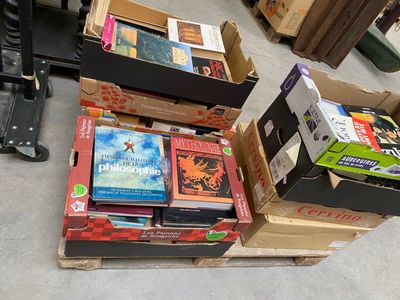 Plusieurs cartons remplis de livres sont empilés les uns sur les autres par terre.