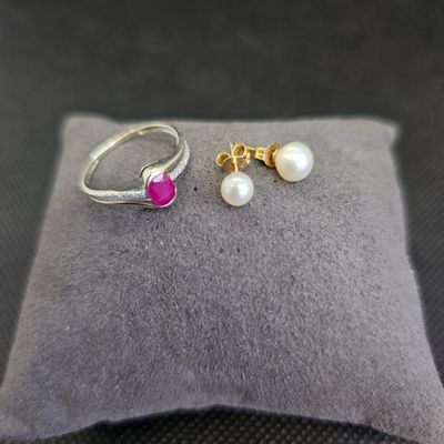 deux bagues et une perle posées sur un coussin, sur un fond noir