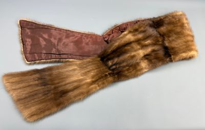 une paire de gants en fourrure marron posés sur une surface blanche