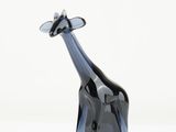 a glass giraffe that is standing on a white surface