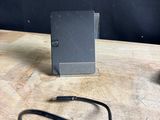 a small black device on a table with a charger attached to it
