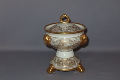 a small white and gold bowl with a gold ring on it