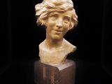 un gros plan sur une sculpture représentant une tête de femme posée sur un bloc de bois