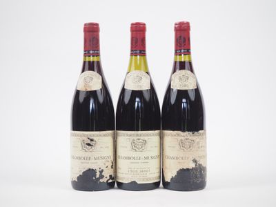 trois bouteilles de vin rouge sont posées côte à côte sur une surface blanche