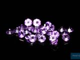 un gros plan sur un bouquet de pierres précieuses violettes posées sur une surface noire