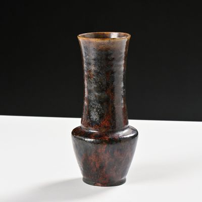 un vase marron posé sur une table blanche