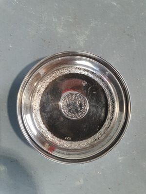 une assiette en argent posée par terre à côté d'une bouteille de vin