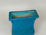 a small blue planter sitting on a white surface