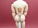 a wooden mannequin standing on a white stand with a red background