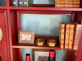 two bottles of wine sitting on a red bookcase