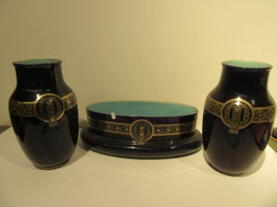 three black vases sitting on a table with a blue plate